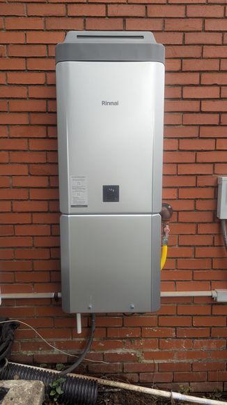 Silver solar battery on a red brick wall; a white pipe and black wires are below.
