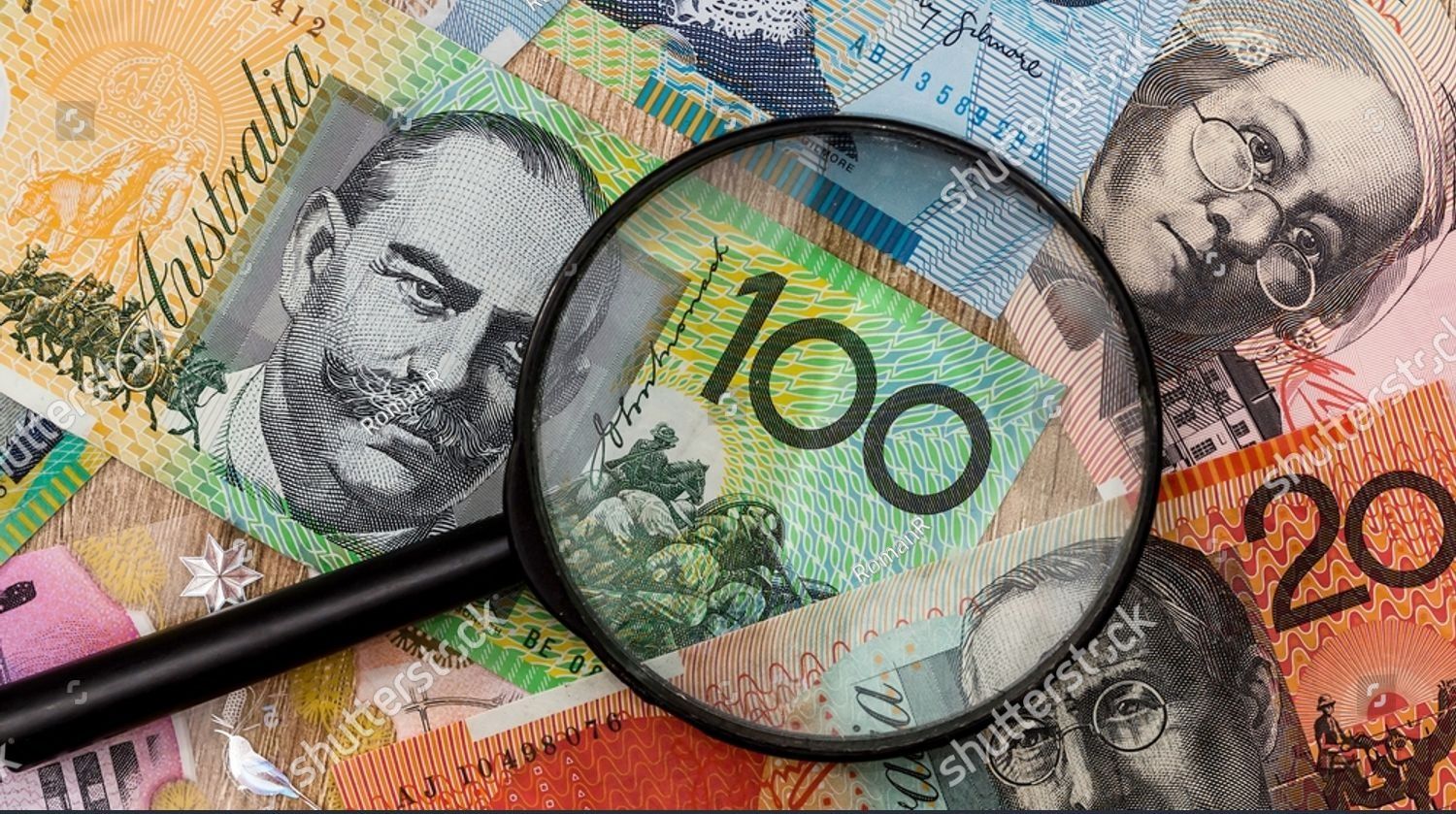 Magnifying glass over Australian banknotes, including a $100 bill.