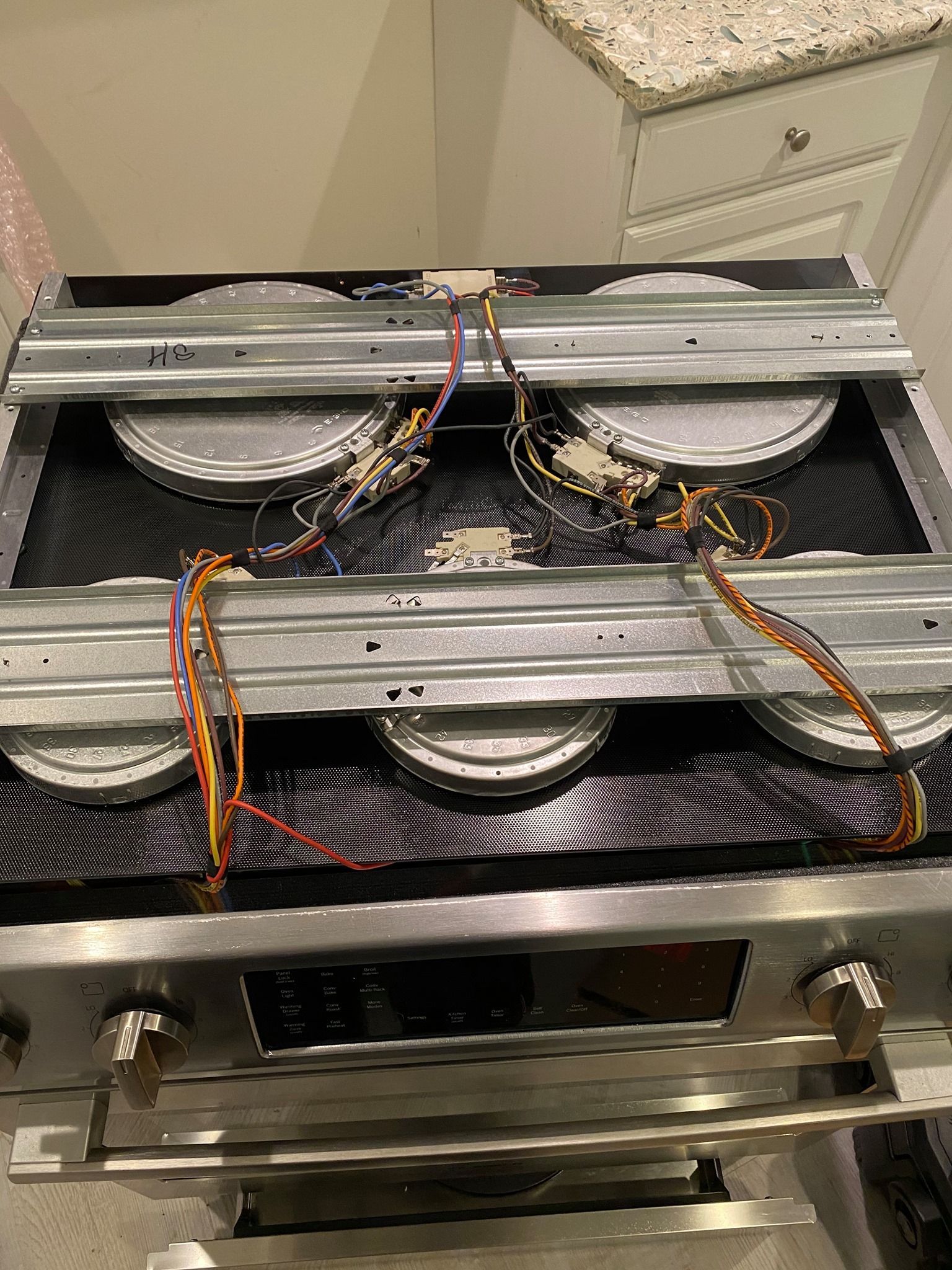 Stovetop with burners, wiring, and control knobs, likely for repair or installation.