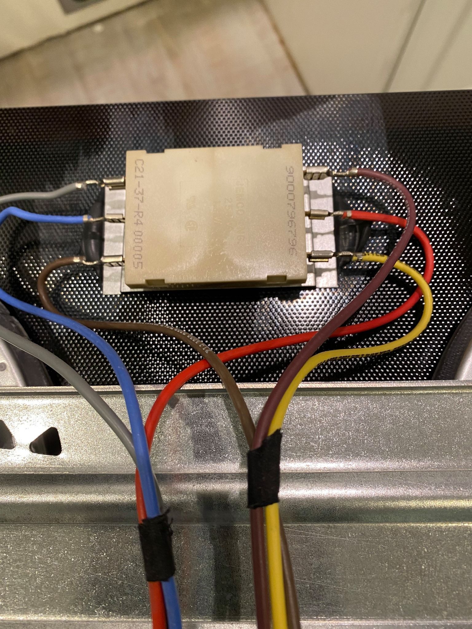 Electrical component with multicolored wires attached to a rectangular, beige-colored block on a black background.