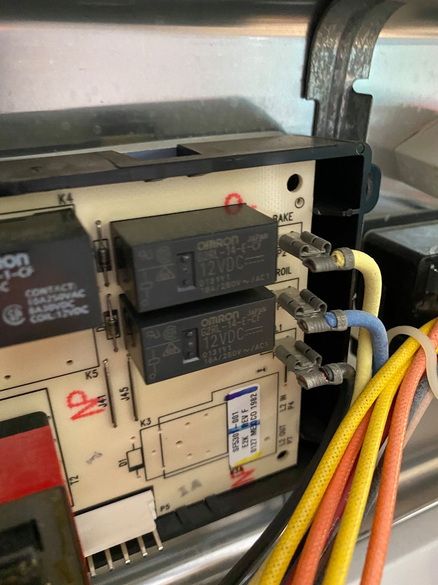 Close-up of a circuit board with two black relays, connected wires (yellow, blue, orange), and labels.