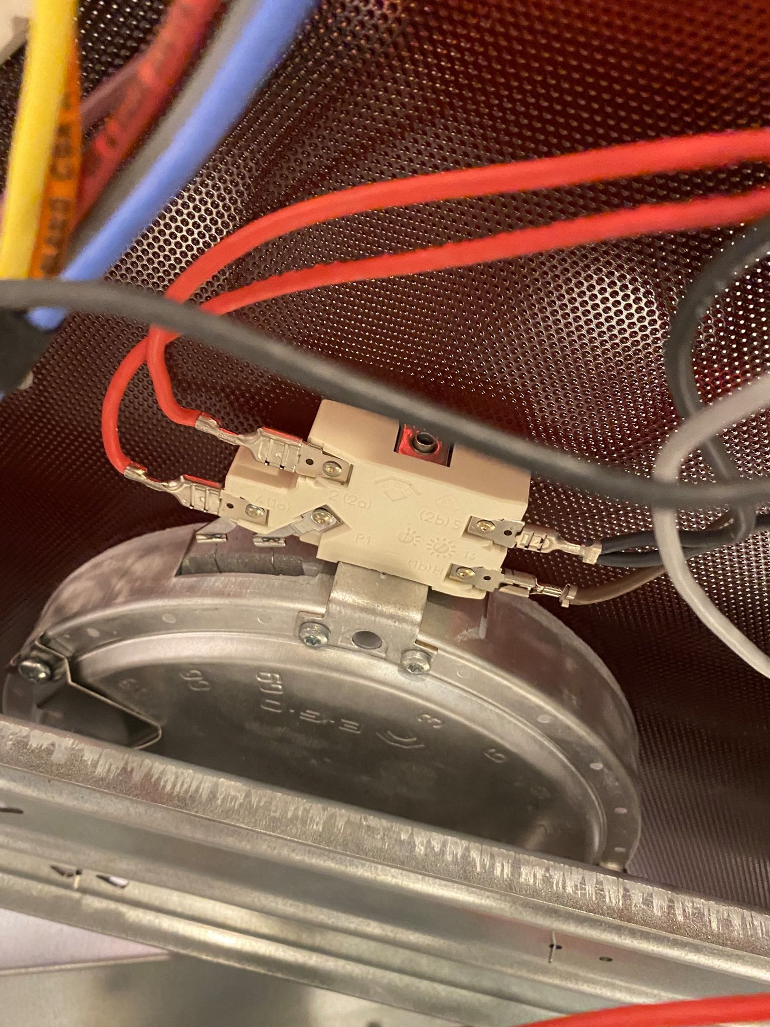 Close-up of a white electrical component with red and other colored wires attached.