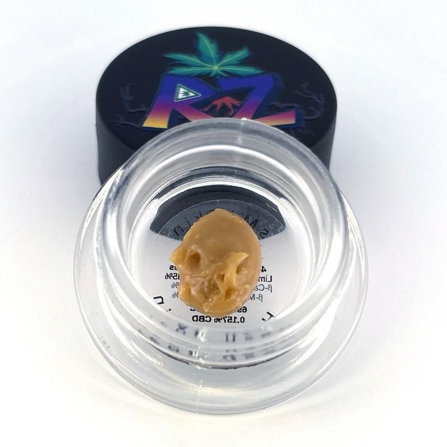 A container of cannabis concentrate shaped like a skull with a branded lid.
