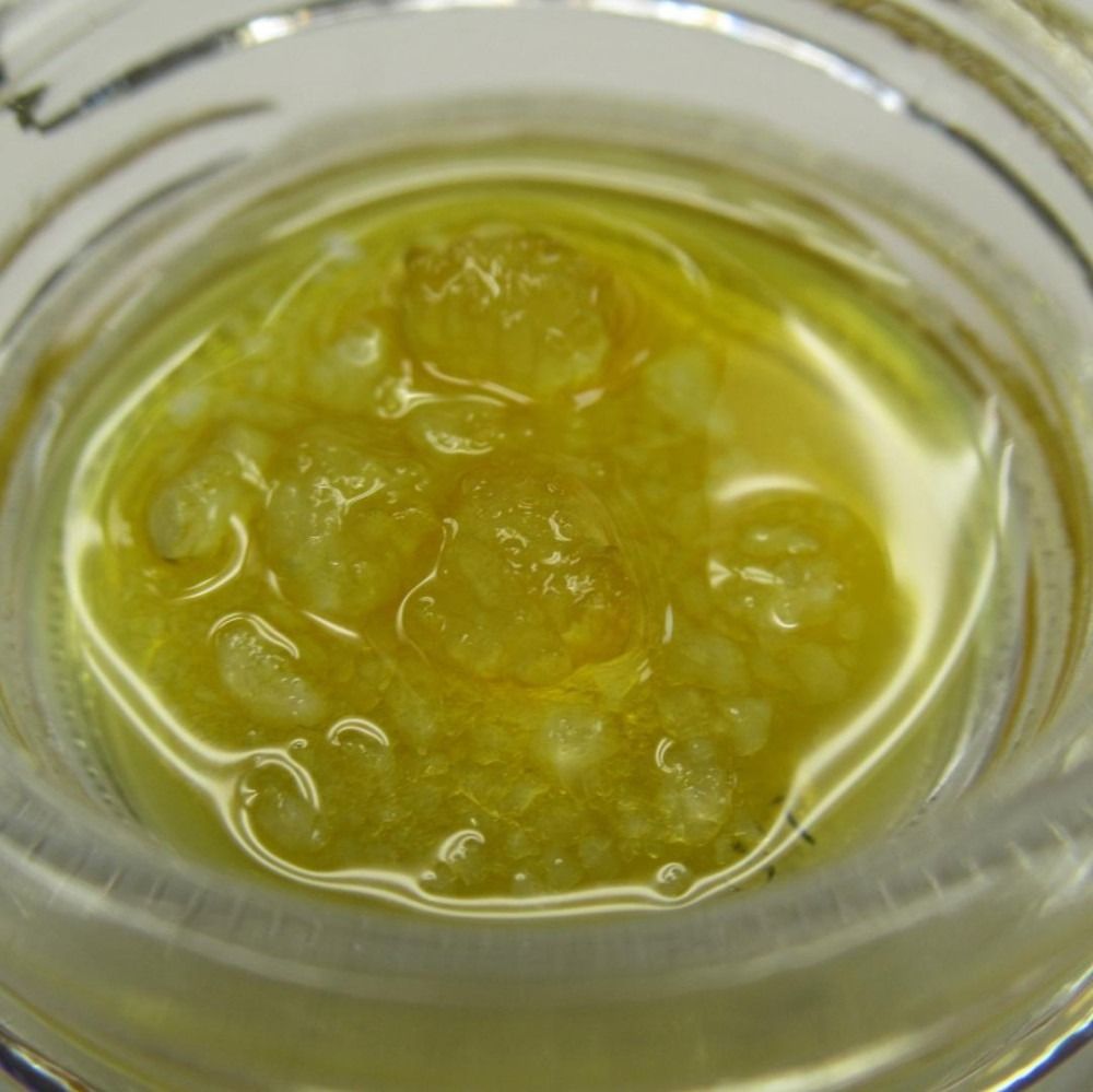 Yellow-gold cannabis concentrate, likely a dab, in a glass jar.