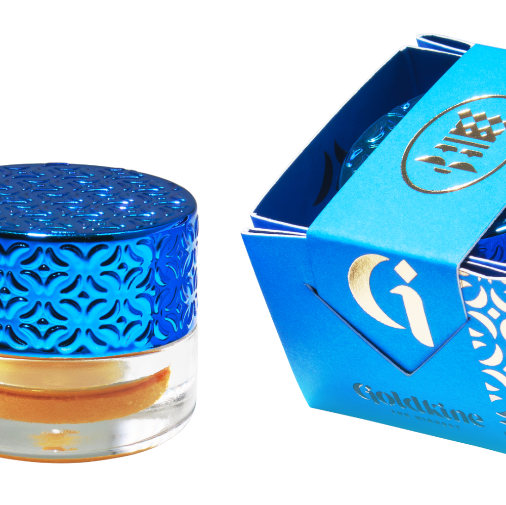 Blue cosmetic jar and packaging, gold script, intricate patterns.