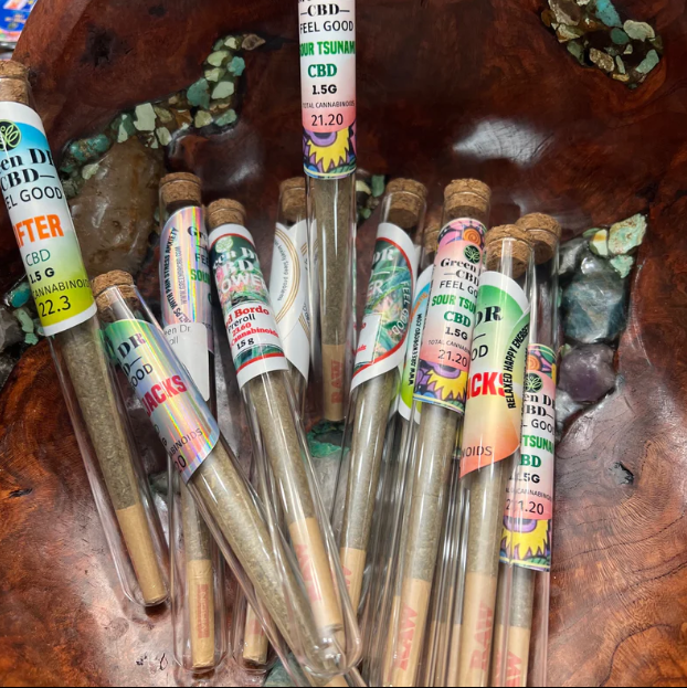 Joints in clear tubes with colorful labels, on a wooden surface.