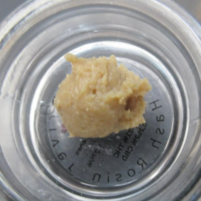 A jar of light brown cannabis rosin concentrate.