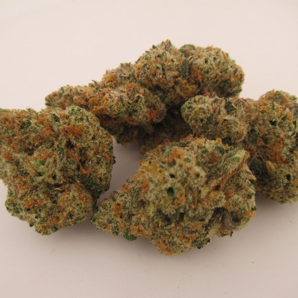 Pile of cannabis buds, green and orange with white trichomes, on a white background.