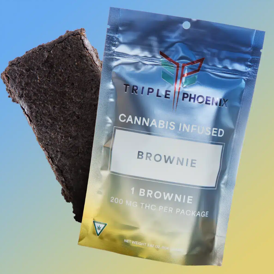 Brownie beside a package of Triple Phoenix cannabis-infused brownie, silver with text, on a gradient background.