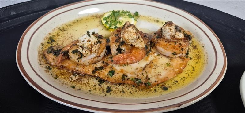 Shrimp scampi served on a white plate with a brown rim.