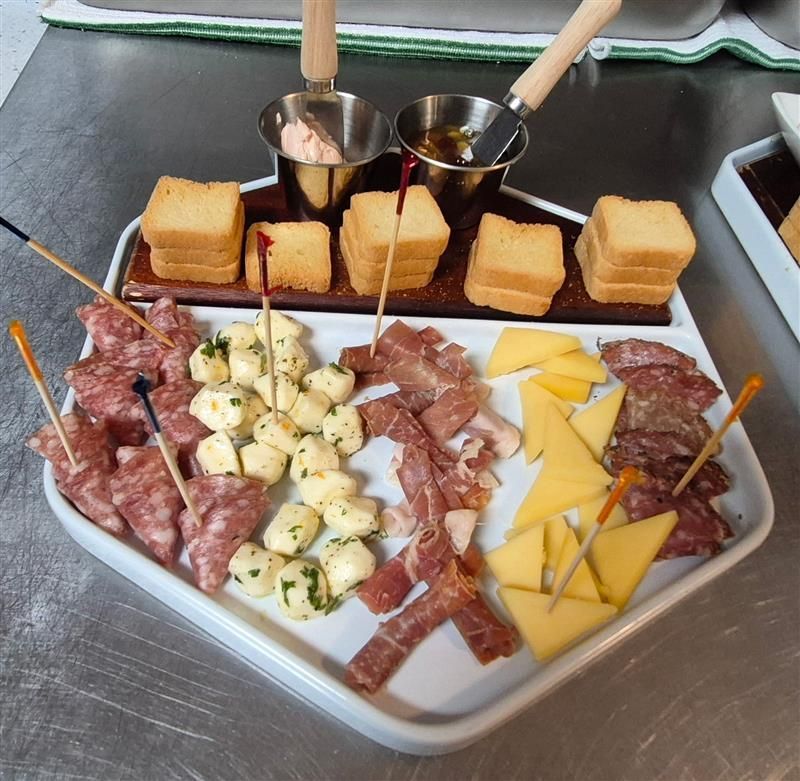Charcuterie board: salami, cheese, mozzarella, with toast, sauces, and skewers.