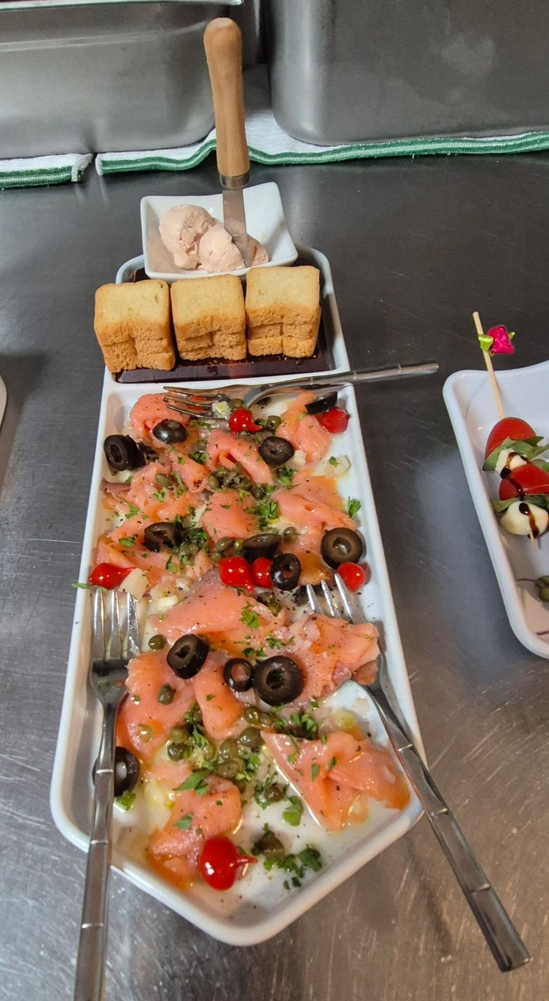 Smoked salmon appetizer with olives, capers, and toast points.