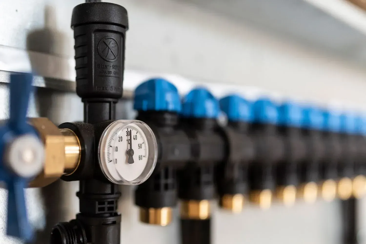 Row of black pipes with blue caps, a pressure gauge, and brass fittings. Row of black pipes with blue caps, a pressure gauge, and brass fittings.