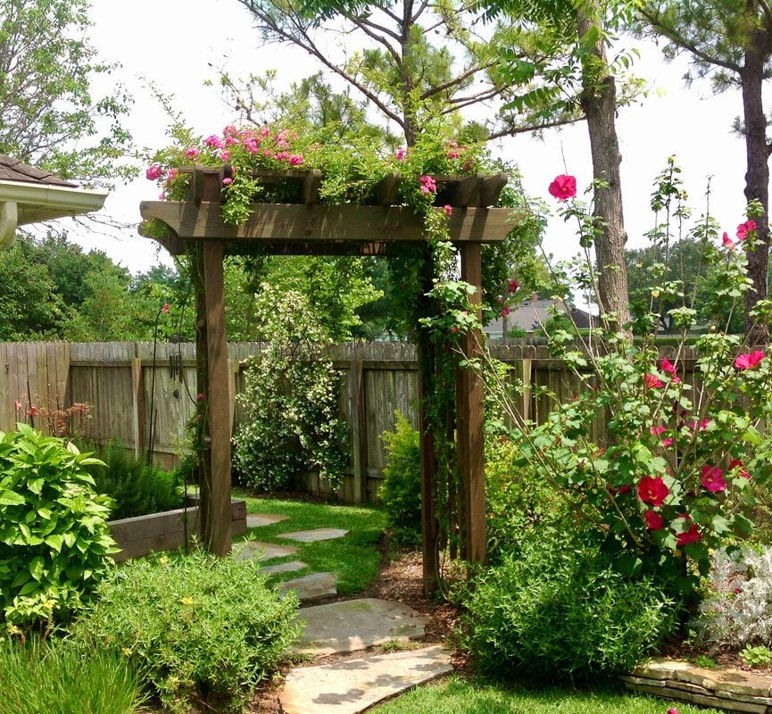 A garden with yellow flowers and purple flowers in front of a wooden fence.