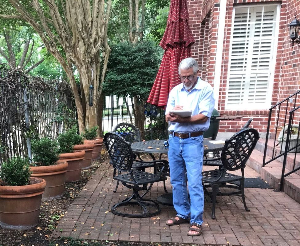 A man is standing on a patio reading a book.