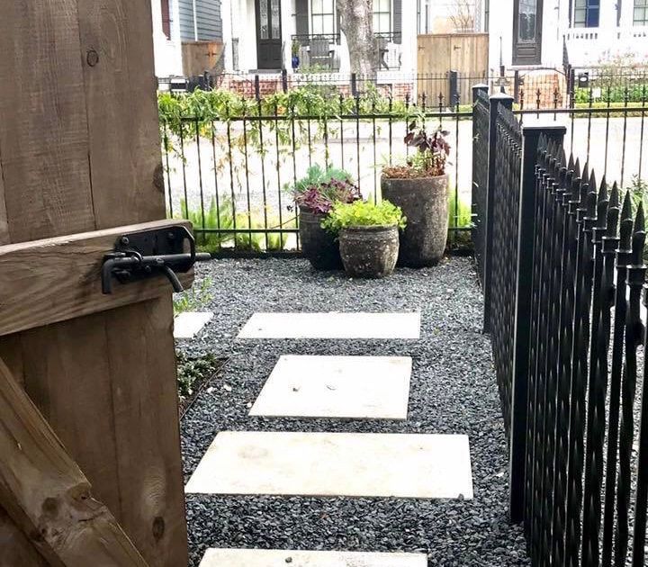 A wooden gate is open to a gravel path leading to a house.