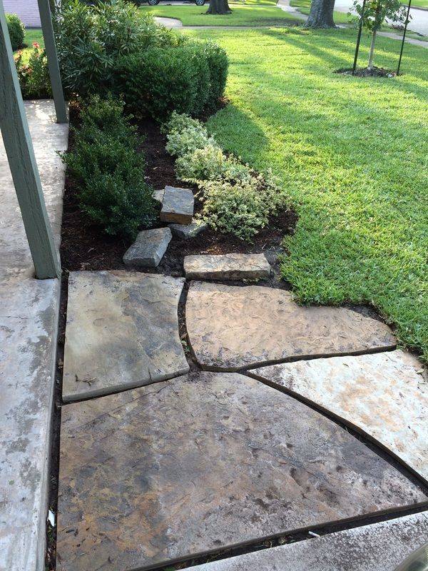 A stone walkway leading to a lush green lawn.