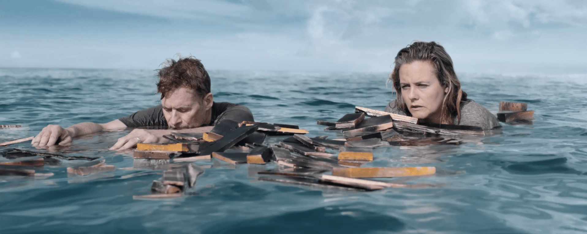Alicia Silverstone and James Tupper on driftwood in the ocean