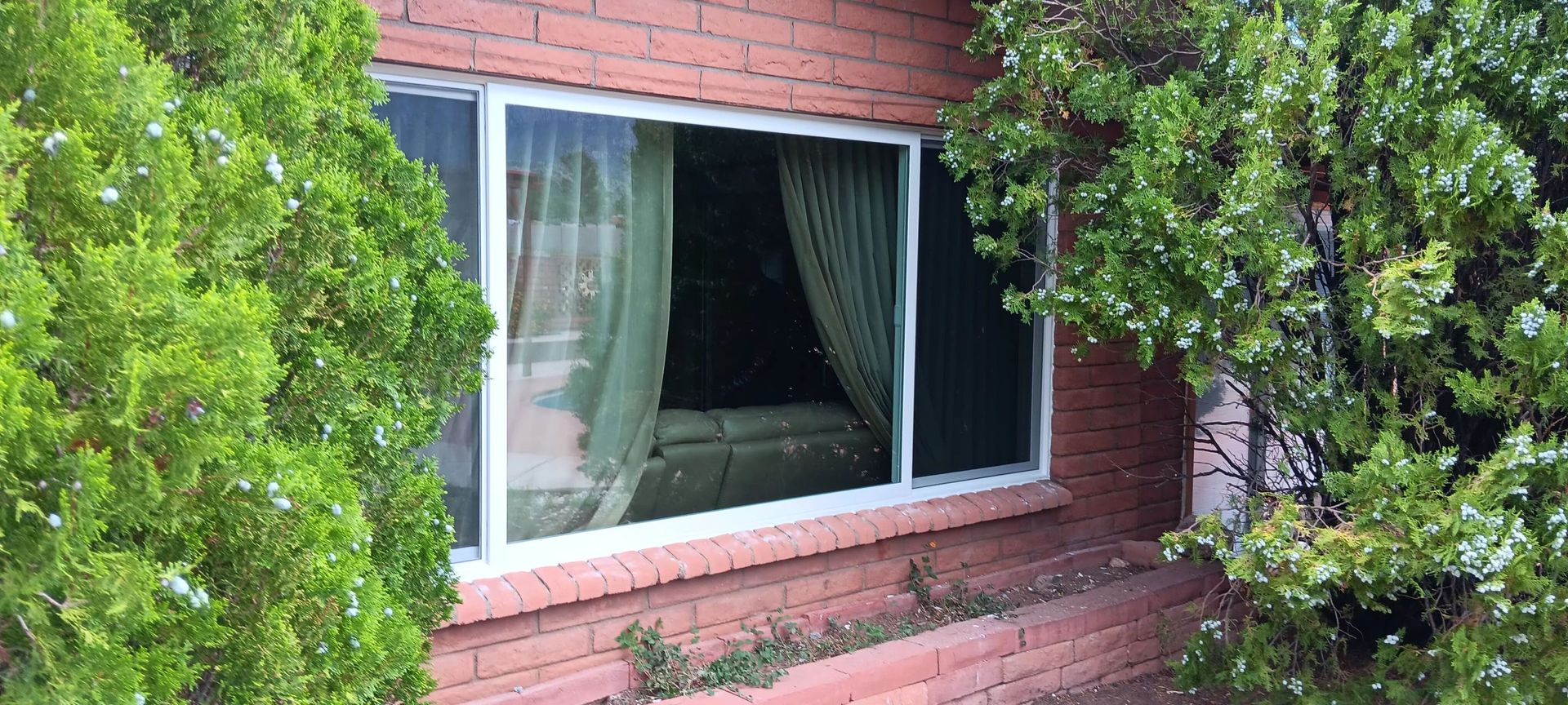 A brick house with a large window surrounded by trees.
