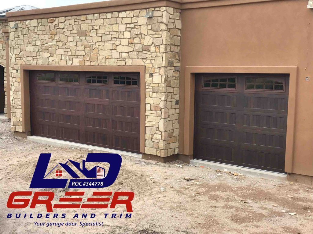 A house with two garage doors and a logo for land greeer builders and trim