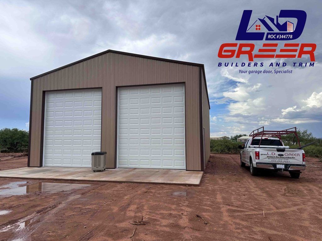 A truck is parked in front of a garage with two garage doors.