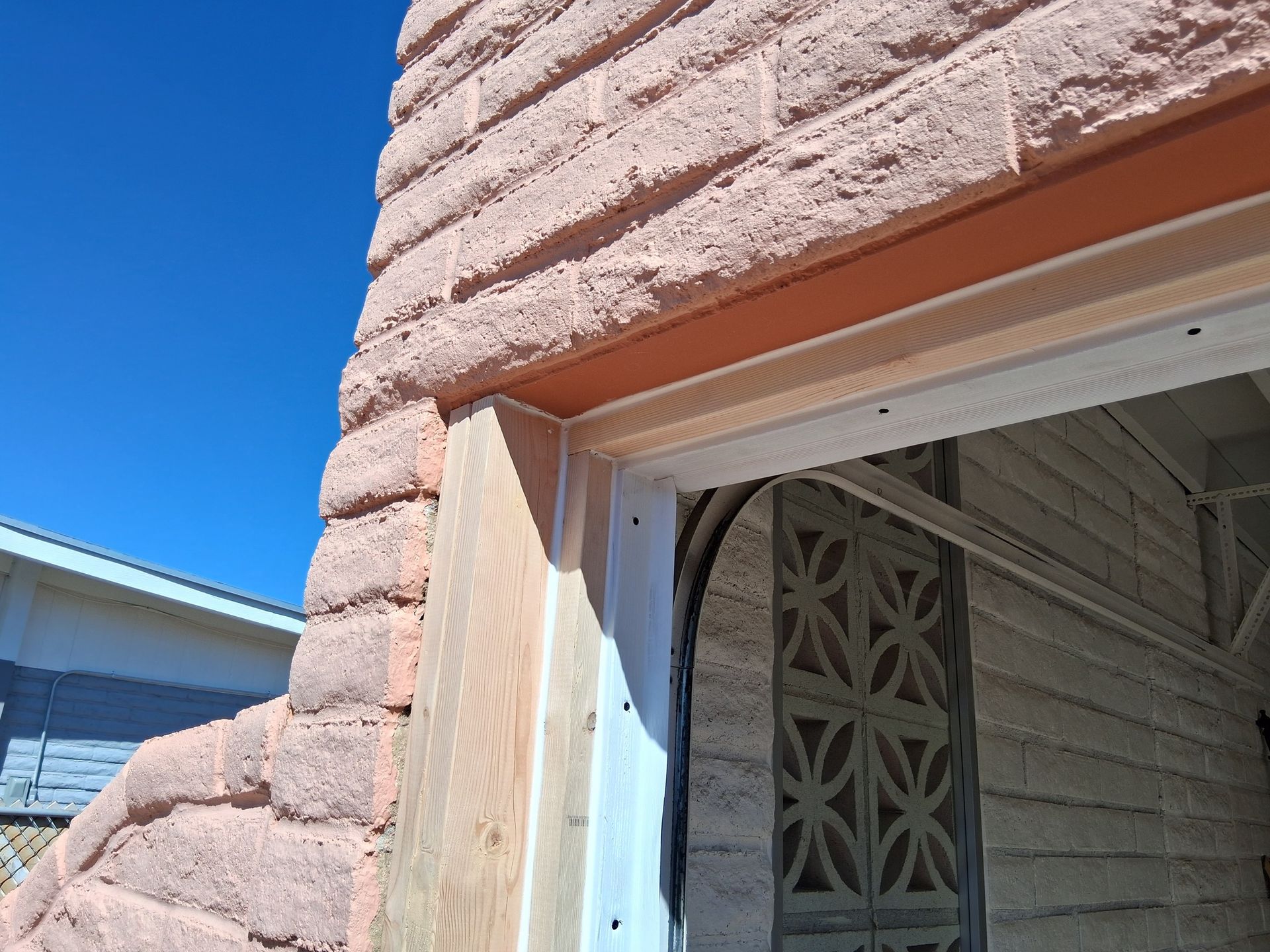 A brick wall with a window in it and a blue sky in the background.