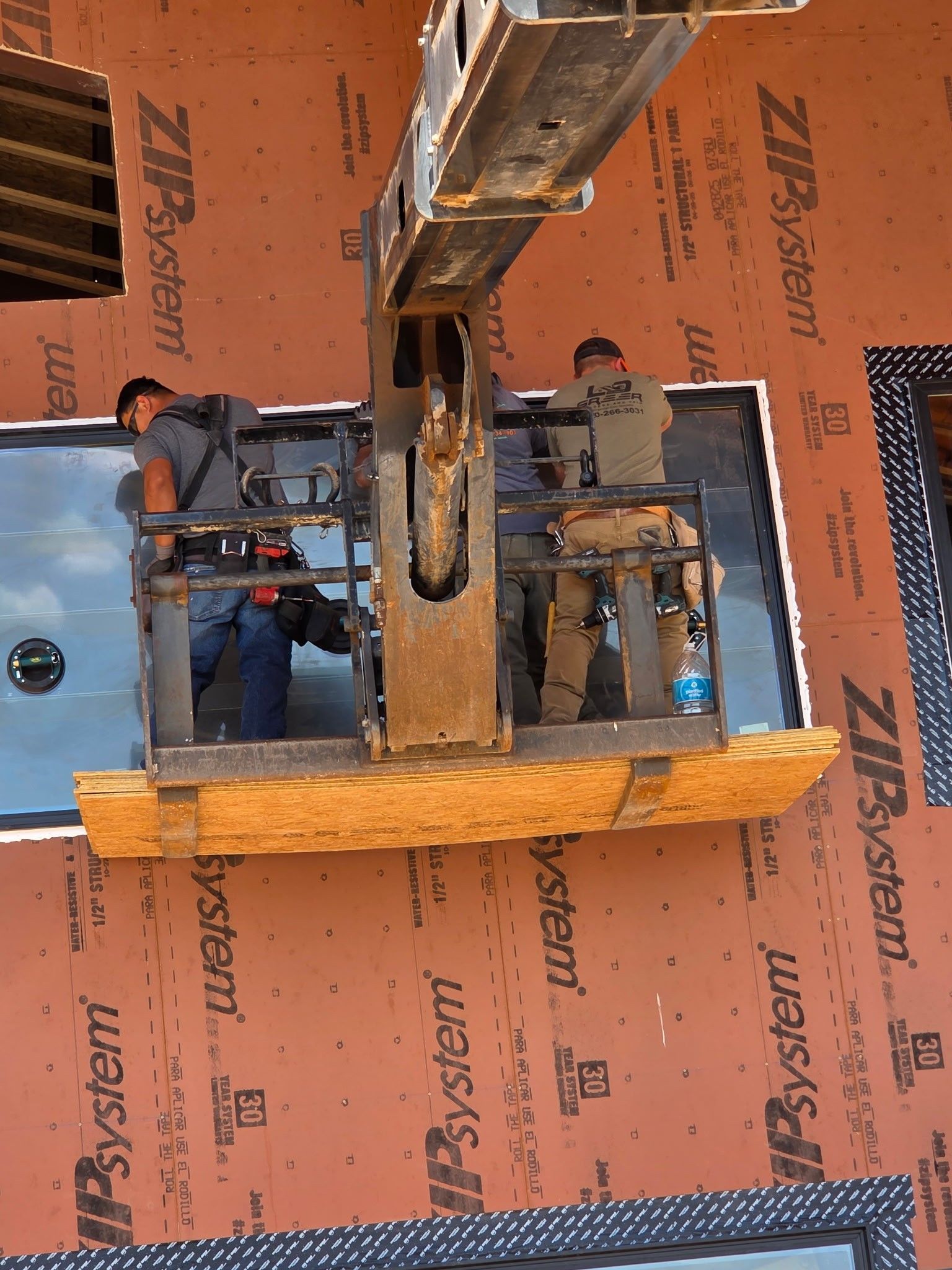 A crane is lifting a window on a building that says zip system