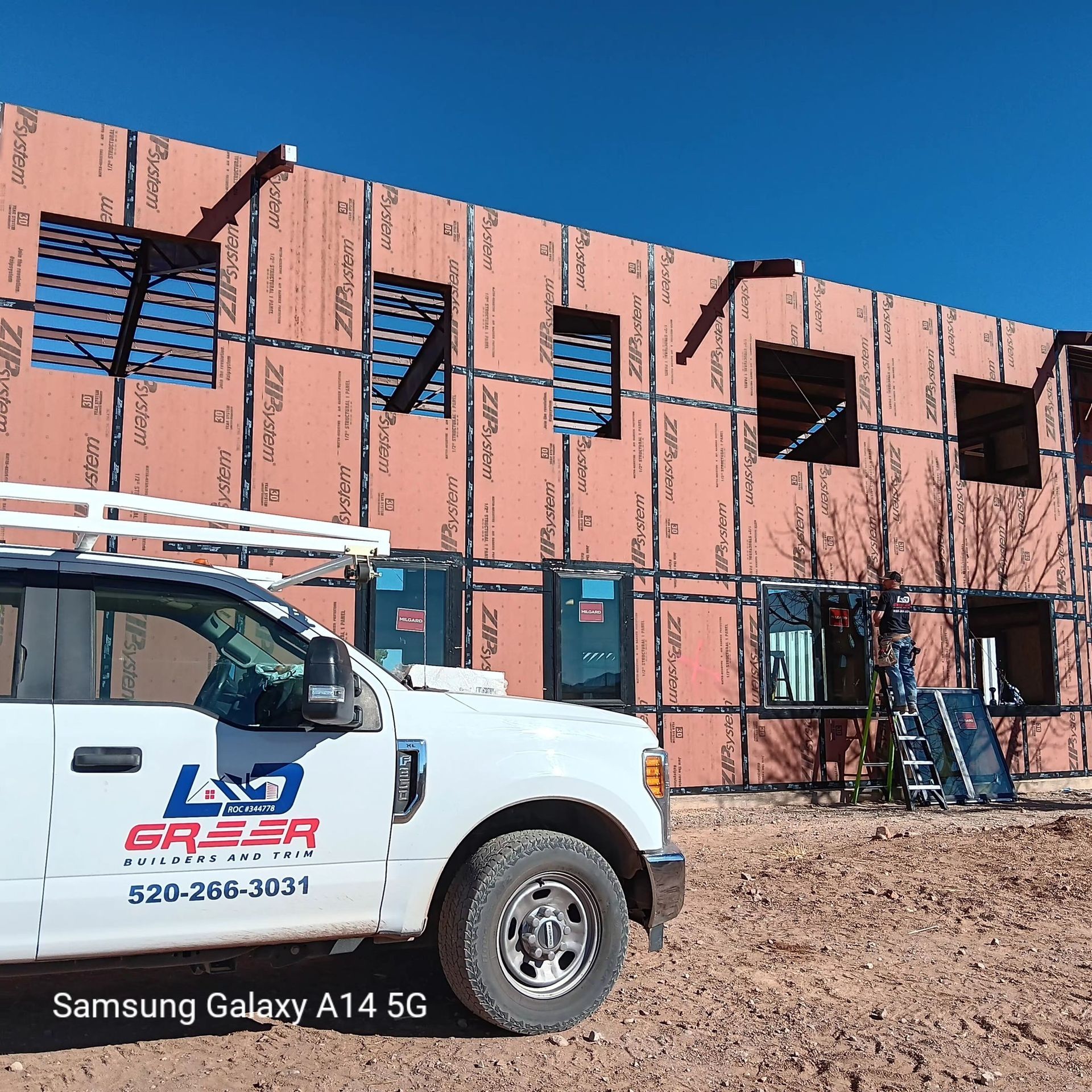 A white truck is parked in front of a building under construction