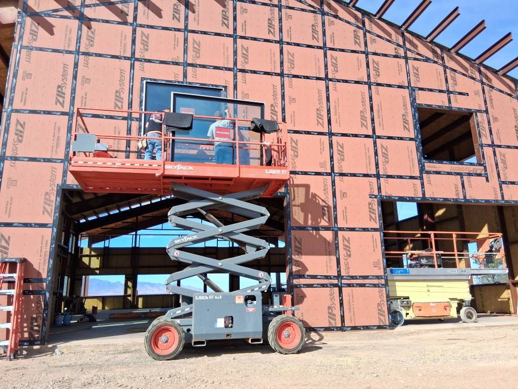 A scissor lift is parked in front of a building under construction