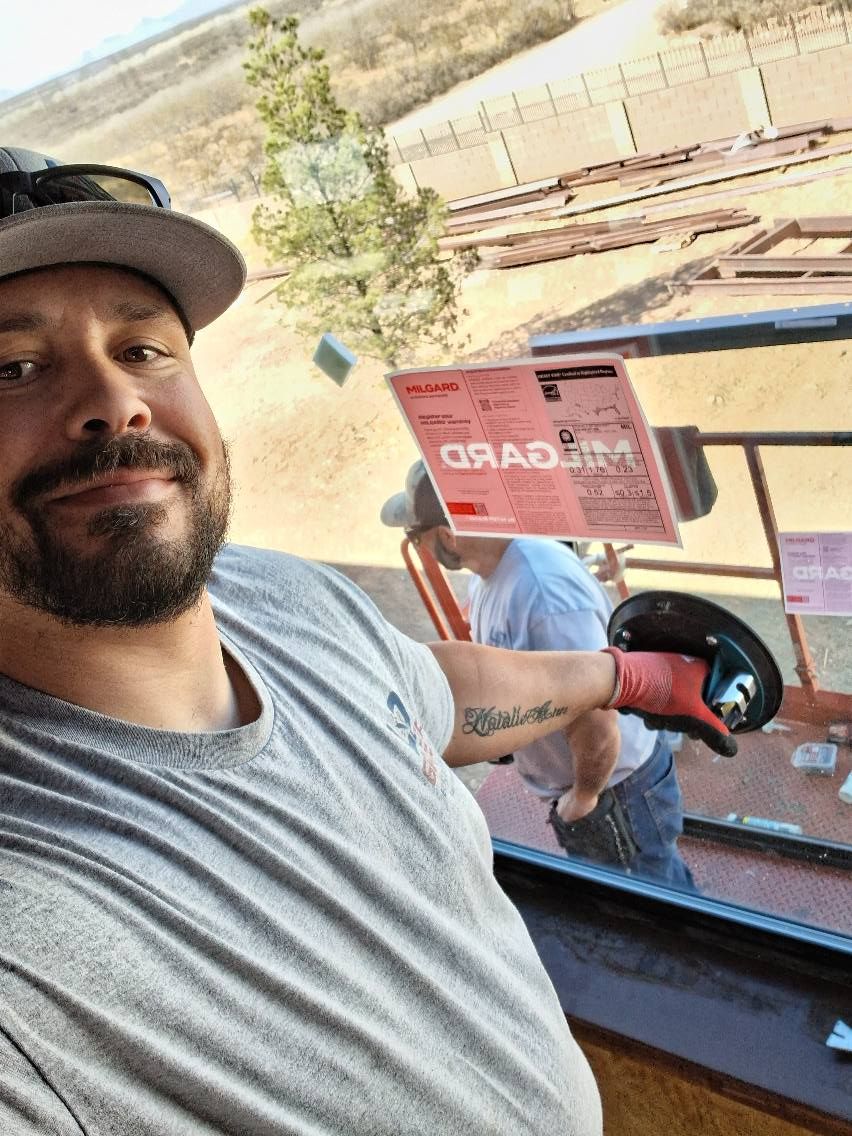 A man with a beard is taking a selfie in front of a window.