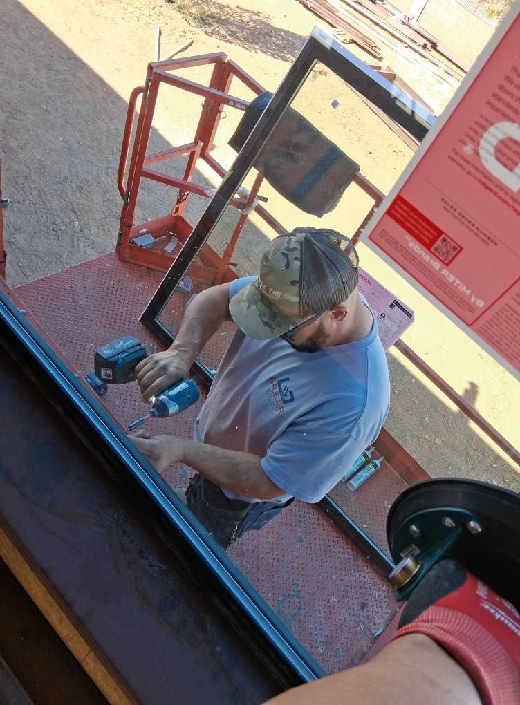 A man is working on a window with a drill.