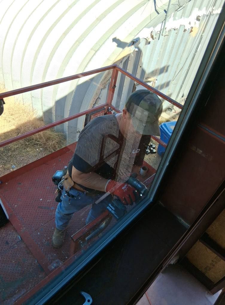 A man is standing on a balcony working on a window.