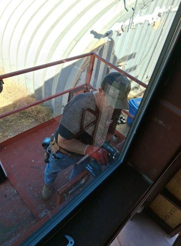 A man is standing on a balcony working on a window.