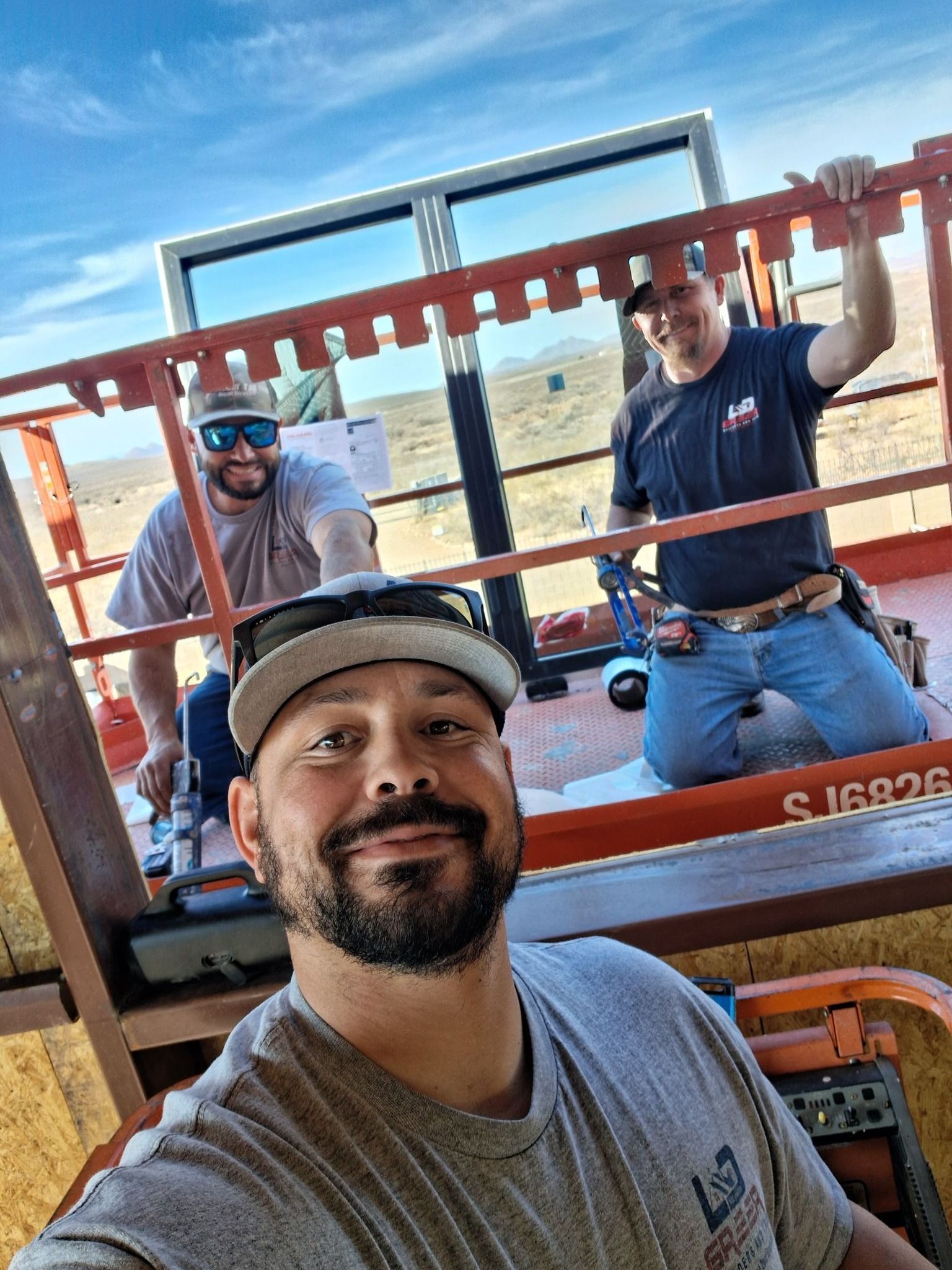 A man is taking a selfie with two other men on a crane.