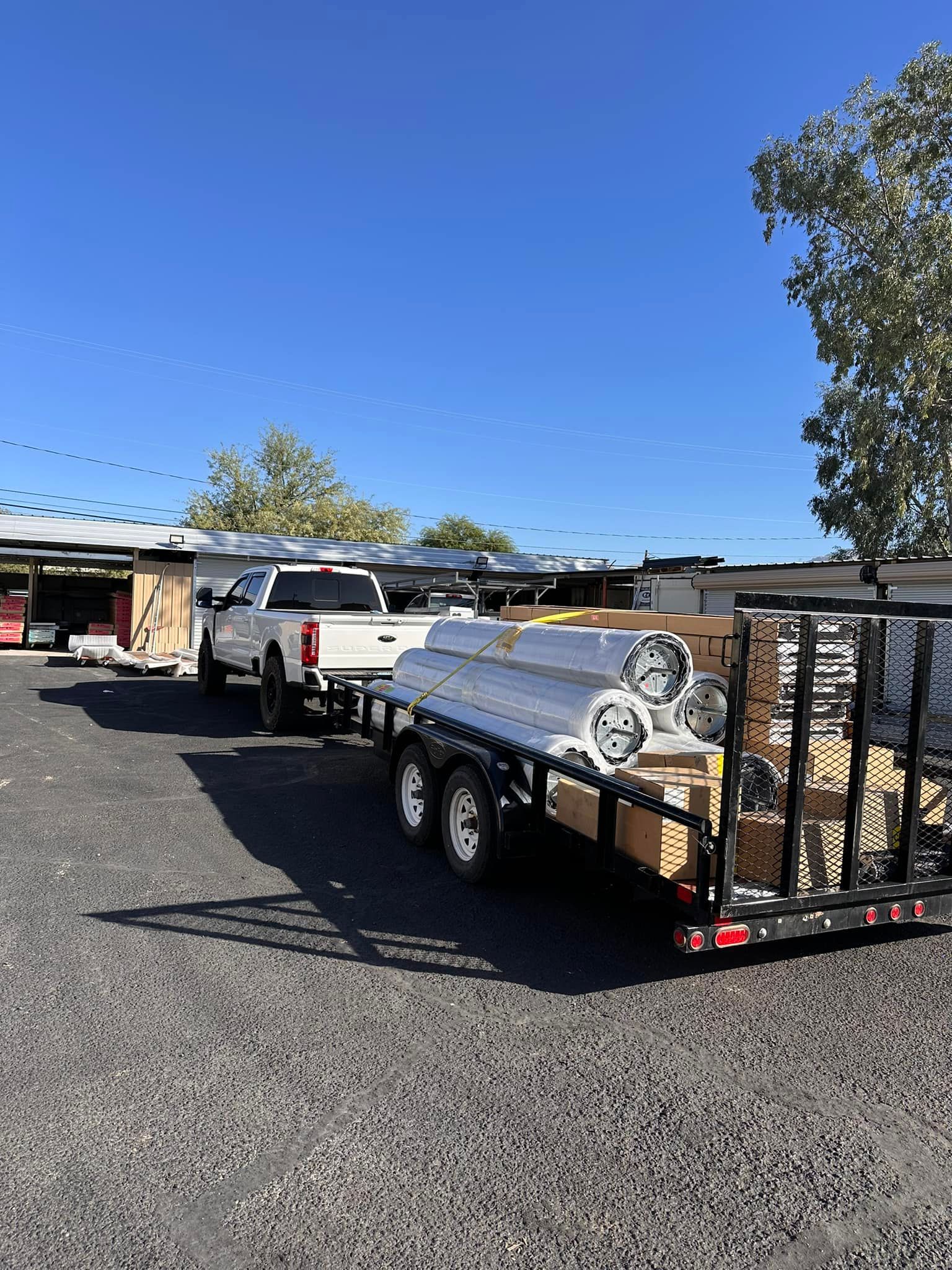 A truck is towing a trailer with a bunch of pipes on it.