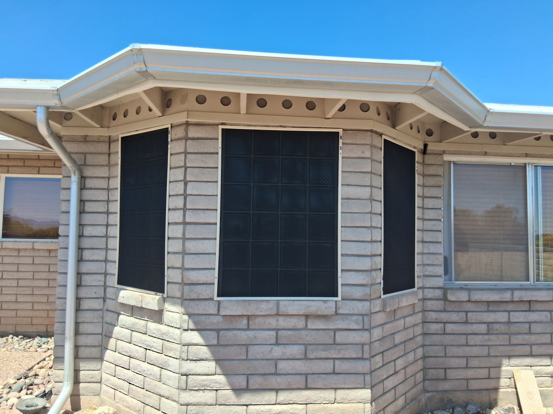 A brick house with a window with a screen on it.