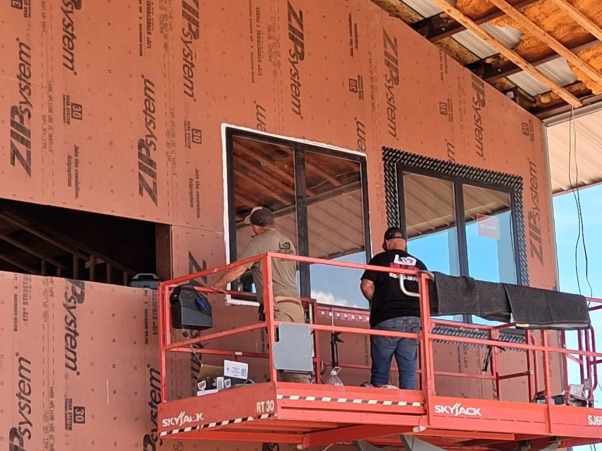 A man is standing on a lift working on a window