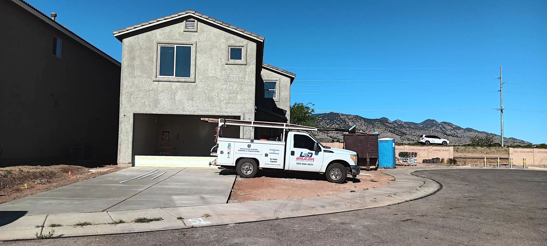A white truck is parked in front of a house under construction.