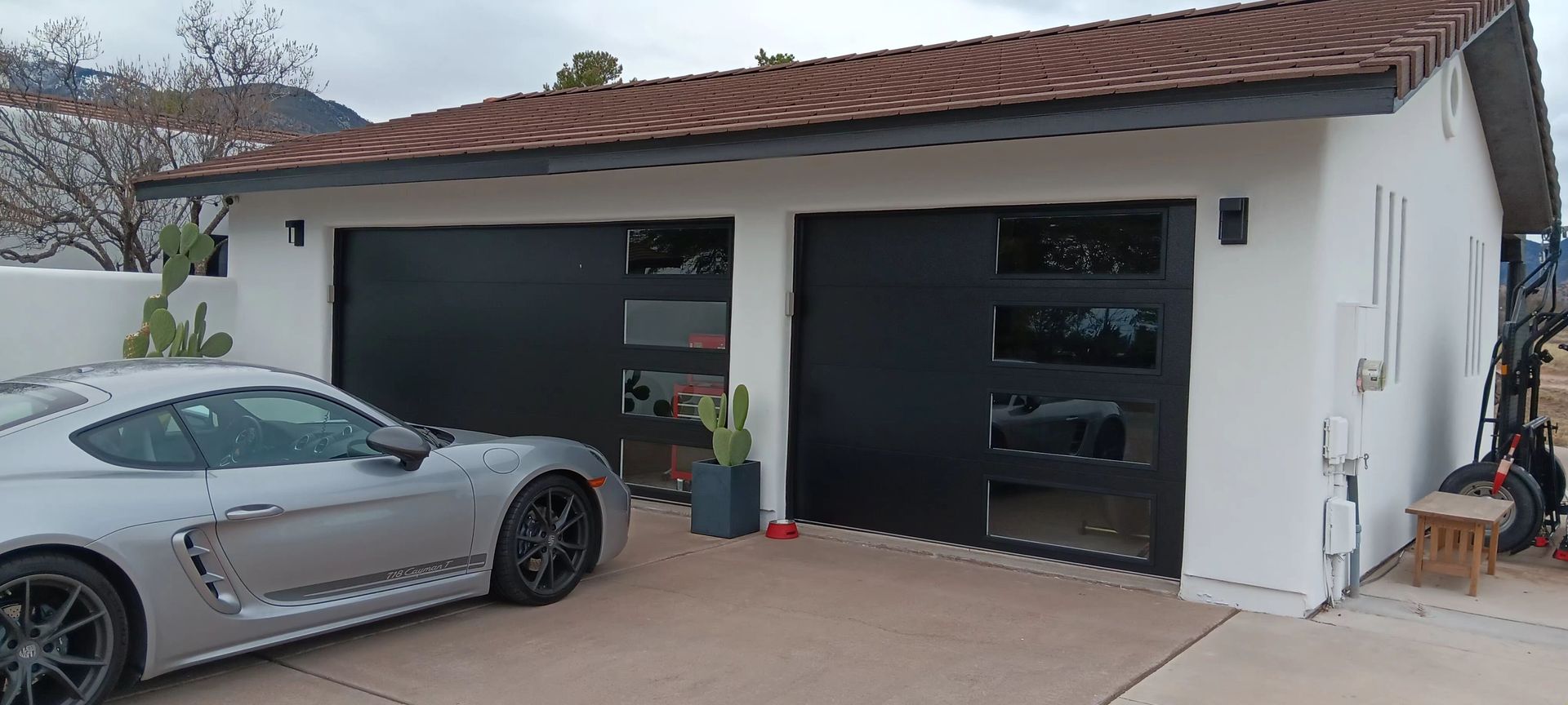 A silver sports car is parked in front of a garage.