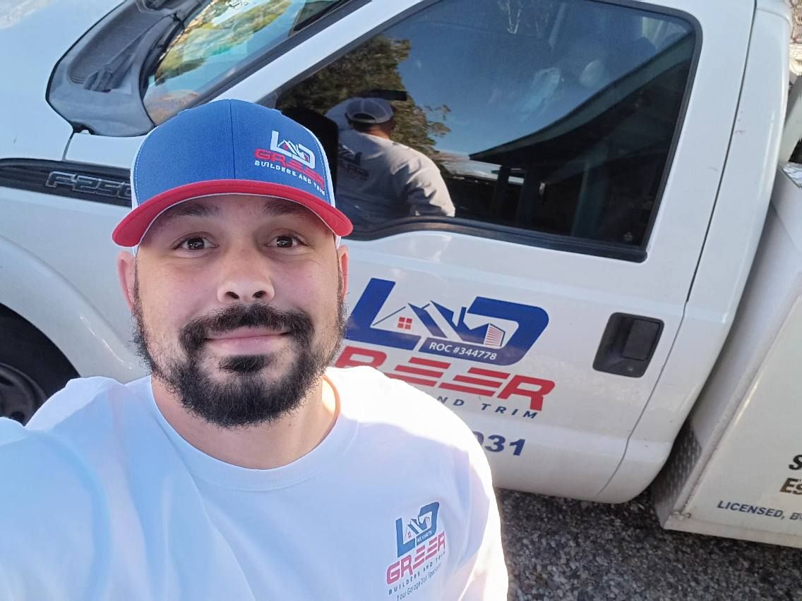 A man with a beard is standing in front of a white truck.