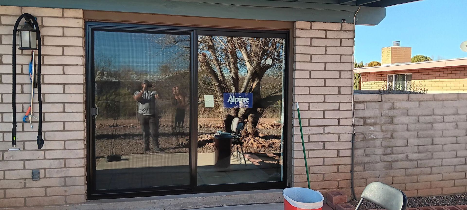 A man is standing in front of a brick building with a sliding glass door.
