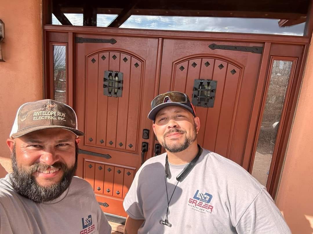 Two men are posing for a picture in front of a wooden door.