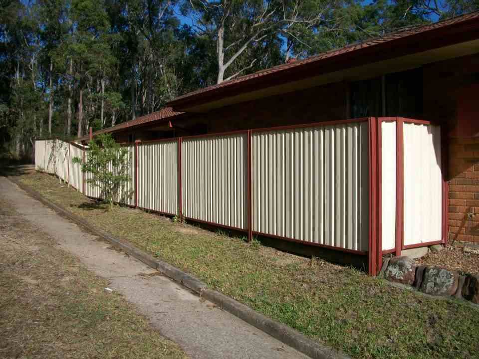 A White and Red Fence Is in Front of A House — Rearden Fencing Pty Ltd in Toronto, NSW