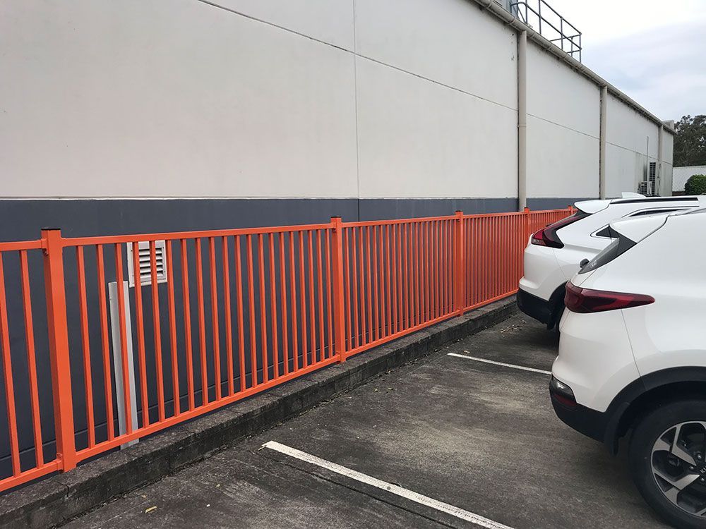 A Row of Cars Parked in Front of a Building With an Orange Fence — Rearden Fencing Pty Ltd in Toronto, NSW