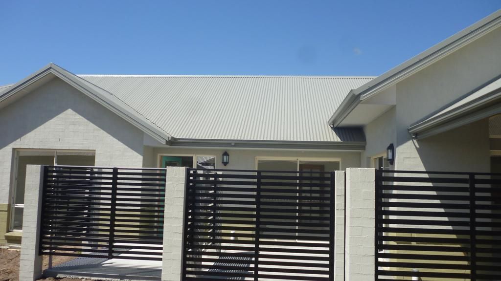A White House with A Black Fence in Front of It — Rearden Fencing Pty Ltd in Toronto, NSW
