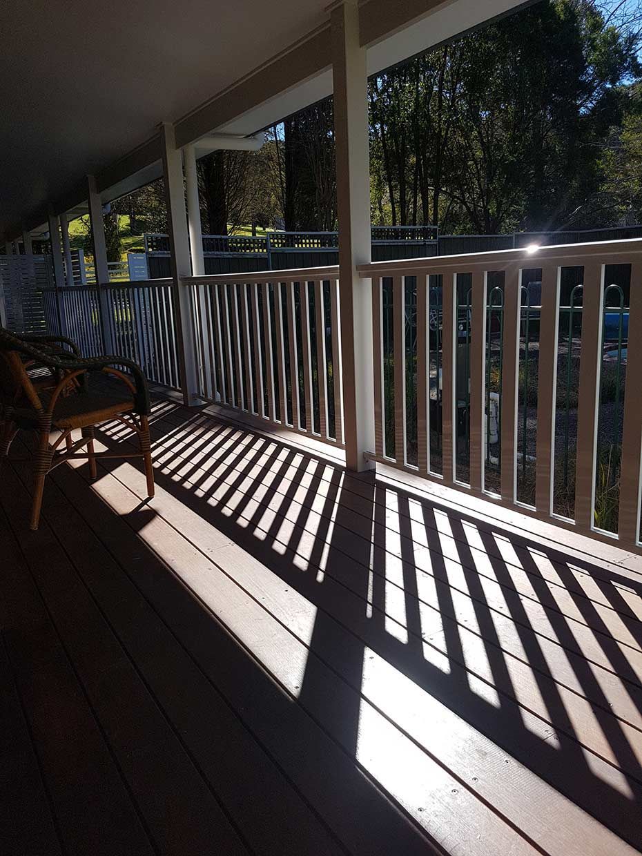 A Porch With a Railing and a Table and Chairs on It — Rearden Fencing Pty Ltd in Toronto, NSW