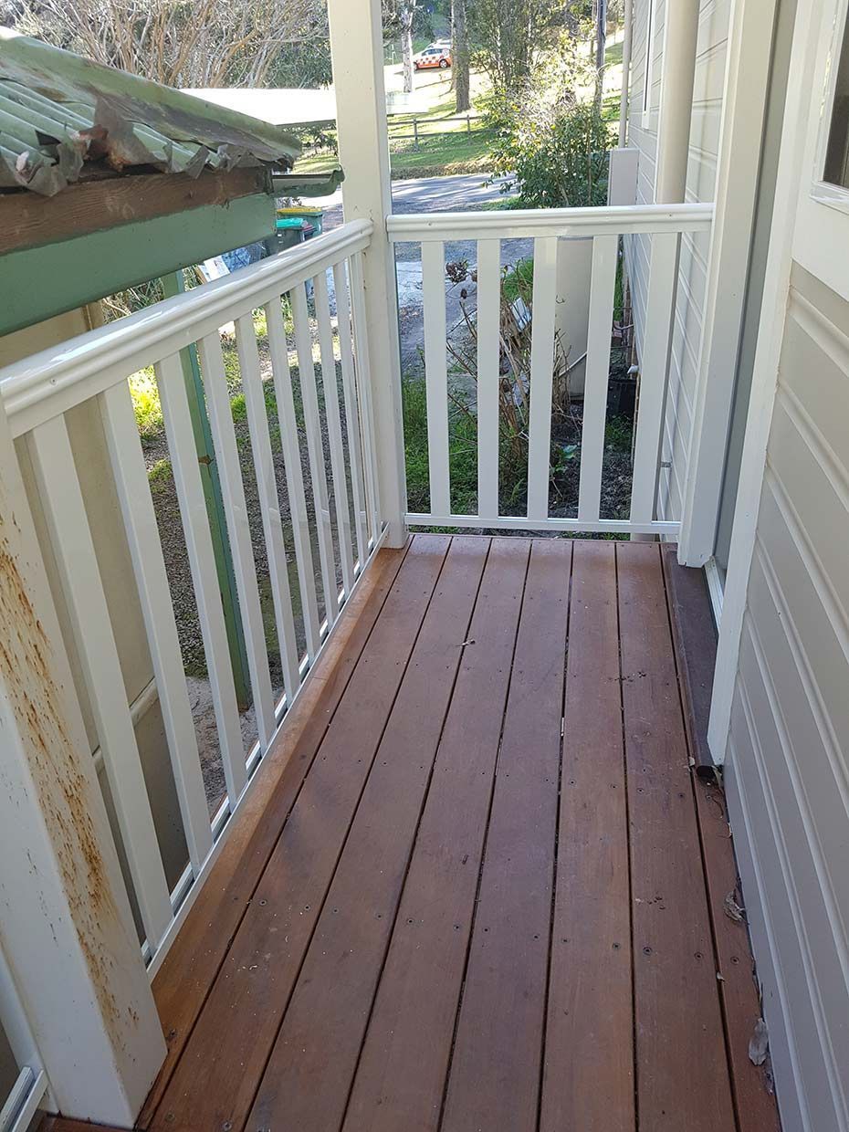 A Wooden Deck With a White Railing on a House — Rearden Fencing Pty Ltd in Toronto, NSW