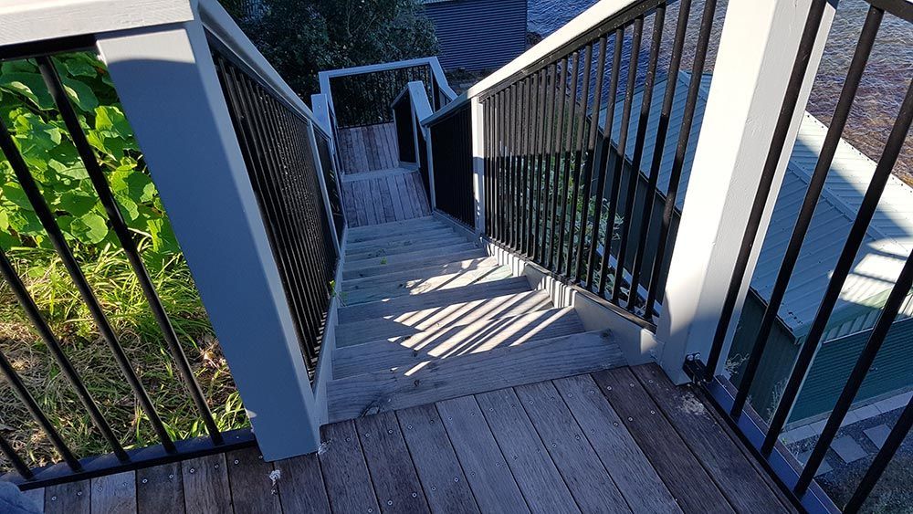 A Set of Stairs Leading Up to a Deck With a Metal Railing — Rearden Fencing Pty Ltd in Toronto, NSW
