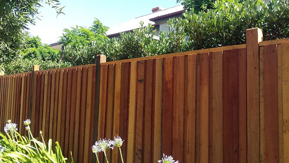 A Wooden Fence With Flowers in Front of It and a House in the Background — Rearden Fencing Pty Ltd in Toronto, NSW