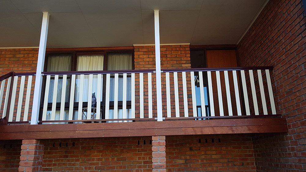A Brick Building With a Balcony With White Railing — Rearden Fencing Pty Ltd in Toronto, NSW